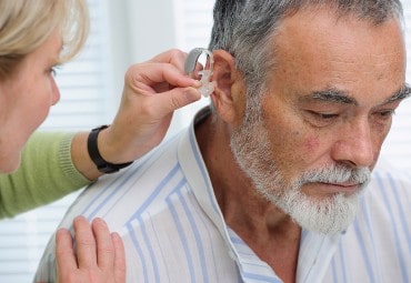 Man getting hearing aid put in ear